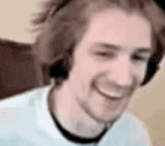 a man wearing headphones is smiling while sitting in front of a computer screen .