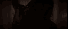 a silhouette of a person 's hand reaching out towards a curtain in a dark room .