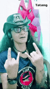 a man wearing a hat and glasses giving the middle finger with the word tatang below him