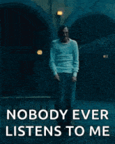 a man is standing in front of a building with the words `` nobody ever listens to me '' written on it .