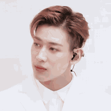 a young man wearing a white shirt and ear buds
