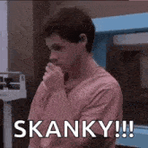 a man in a pink shirt is covering his mouth with his hand and says skanky !