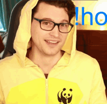 a man wearing glasses and a yellow hoodie with a panda on the front