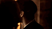 a close up of a young man 's face in a dark room with a lamp in the background .