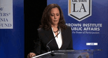 a woman stands at a podium in front of a sign that says brown institute