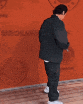 a man in a suit is standing in front of a wall that says le village