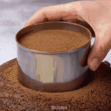a person is making a cake with a stainless steel ring that says mr.cakes on the bottom