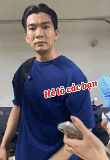 a man wearing a blue shirt that says " he lo các ban " on it