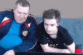 a man and a boy are sitting on a couch looking at a laptop .