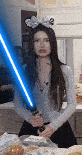 a woman is holding a light saber in front of a bag of bakery products