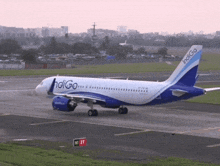 a blue and white indigo airplane is taking off from an airport runway