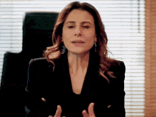 a woman wearing a black jacket and gold buttons is talking