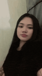 a young woman with long black hair is taking a selfie while sitting on a bed .