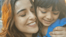 a woman holding a little girl in her arms and smiling