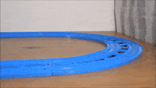 a toy train is going around a blue track on a table