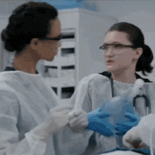 two female doctors are shaking hands in a hospital room while talking to each other .