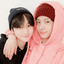 a boy wearing a pink hoodie and a boy wearing a black beanie are posing for a picture