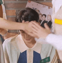 a man wearing glasses is being patted on the forehead by another person .