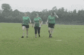 three women are walking on a field wearing green shirts and shorts .