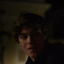 a close up of a young man 's face with a dark background .