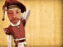 a man in a red costume is holding a sword and a hat .