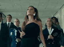 a woman in a black dress is standing in a hallway surrounded by other women