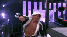 a man in a white hooded robe stands in front of a wrestling ring