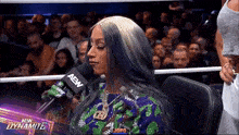 a woman sitting in front of a microphone that says aew dynamite on it