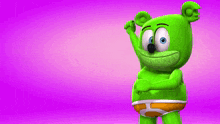 a green gummy bear is holding a red heart on a pink background