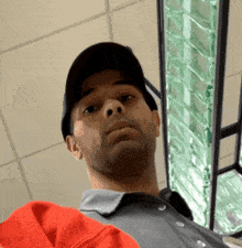 a man wearing a hat and a grey shirt is looking up at the camera