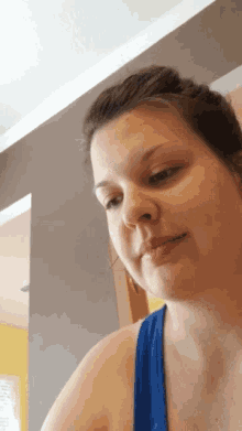 a woman wearing a blue tank top is looking down