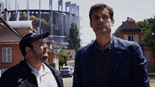 two men standing next to each other in front of a building that says tv on the bottom