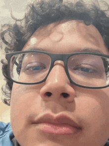 a close up of a person 's face with glasses and curly hair