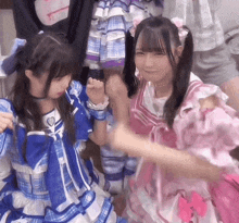 two girls in pink and blue dresses are standing next to each other .
