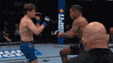 a man wearing a pair of ufc gloves is boxing another man