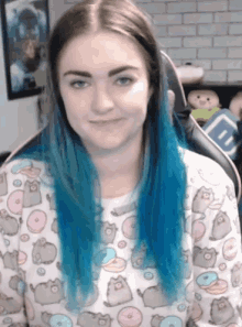a girl with blue hair is wearing a sweater with donuts on it