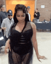 a woman in a black dress is standing in a room with people standing around her .