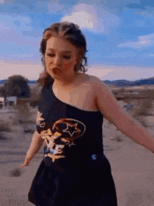 a woman in a black dress is standing in the desert .
