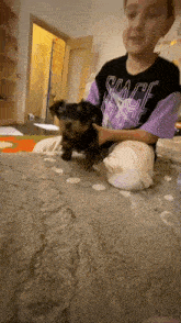 a girl is playing with a small dog on a carpet .