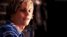 a young man with blonde hair and a blue shirt is smiling .