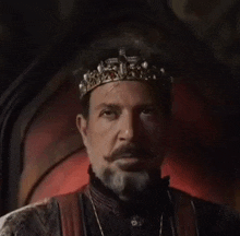 a man with a beard and mustache is wearing a crown and sitting on a throne .