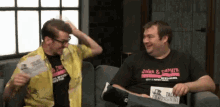 two men are sitting on a couch and one has a shirt that says " jake & vampire " on it