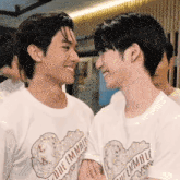 a couple of young men are standing next to each other and smiling at each other .