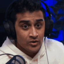 a close up of a man wearing headphones and a white hoodie