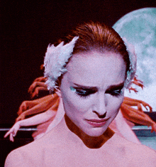 a woman with white feathers in her hair looks down