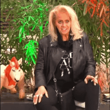 a woman in a black leather jacket is sitting in front of a stuffed animal of a lion .