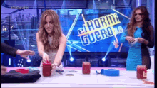 two women are sitting at a table in front of a screen that says el horrible guero