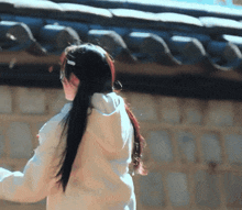 a woman in a white hoodie stands in front of a tiled roof