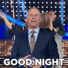 a man in a suit and tie is holding a ball and says good night