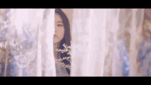 a woman is looking out of a window through a white lace curtain .